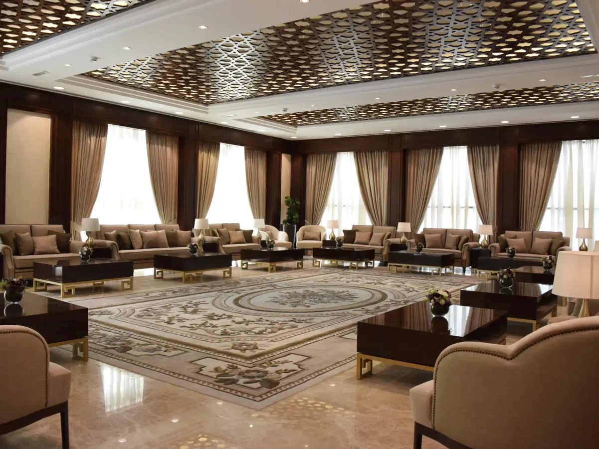Wide view of the main majlis area with plush seating, gold-accent tables, and curtains